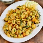 A serving dish with Lebanese spicy potates served with lemon slices.