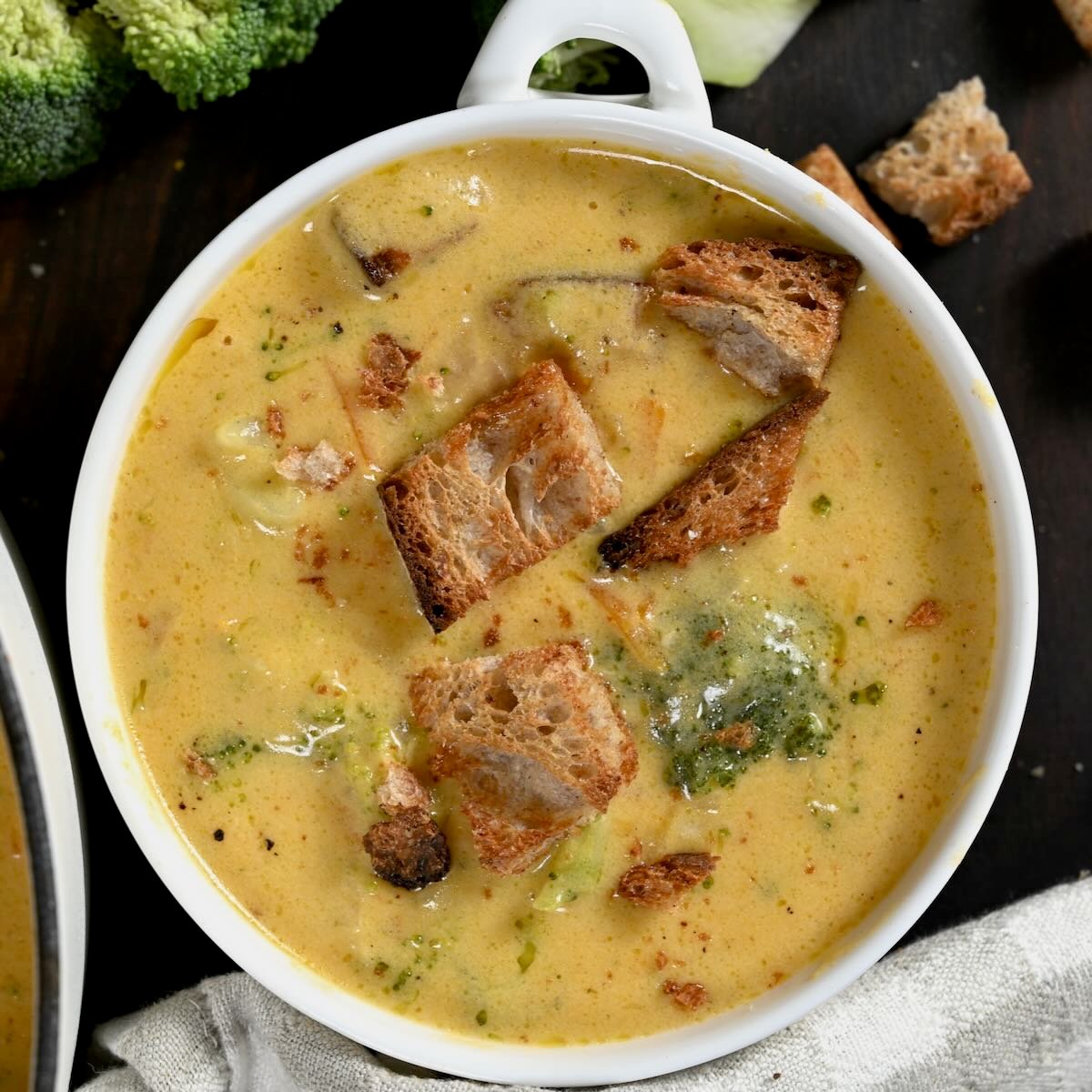 Broccoli cheddar soup served in a small white bowl and topped with croutons. - 43