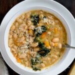 A serving of white bean soup topped with an extra shaving of parmesan. - 14