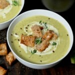 A serving of zucchini soup topped with croutons, cracked pepper, and fresh thyme. - 14
