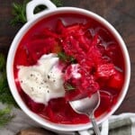 A serving of borscht soup topped with sour cream and fresh dill. - 13
