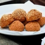 Fried falafel, some topped with sesame seeds, arranged on a tissue-lined plate. - 18