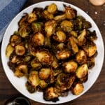 A serving dish with air fryer Brussels sprouts topped with balsamic glaze and salt flakes. - 15