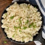 A serving dish with homemade cauliflower rice topped with parsley. - 14