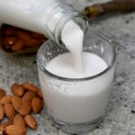 Pouring homemade almond milk into a small glass. - 14
