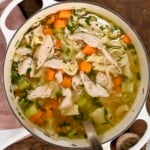 A large pot filled with homemade turkey soup with carrots, celery, and pasta.