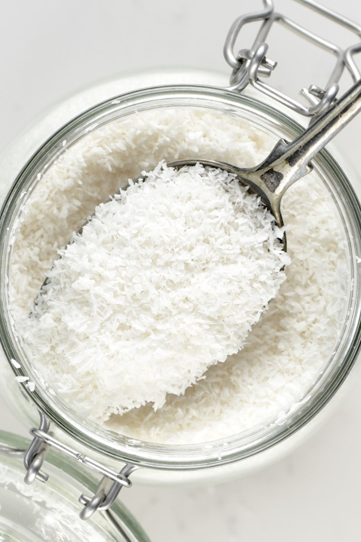 A spoonful of desiccated coconut over a jar.