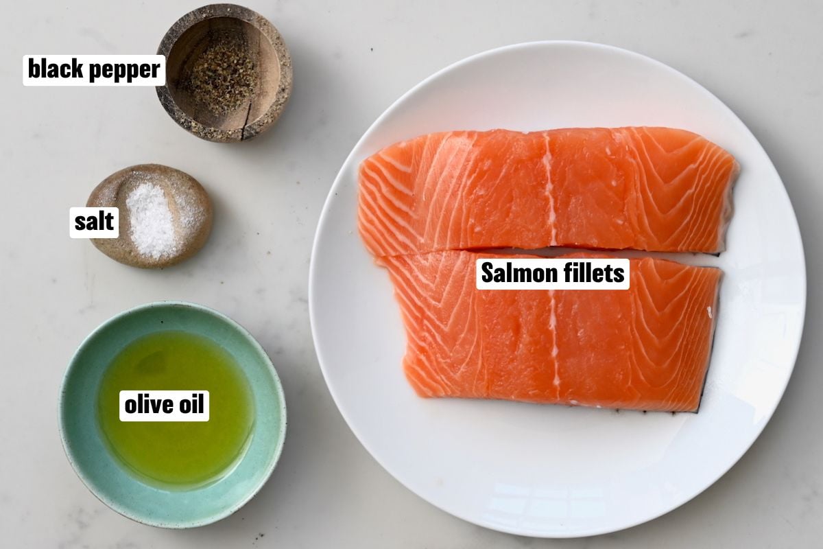 Grilled salmon ingredients: Two raw salmon fillets, olive oil, salt, and black pepper. - 2