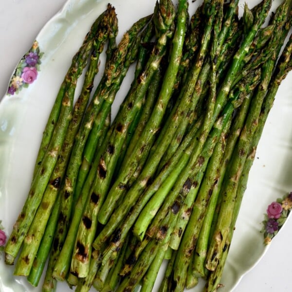 Close-up square photo of grilled asparagus on a green plate.