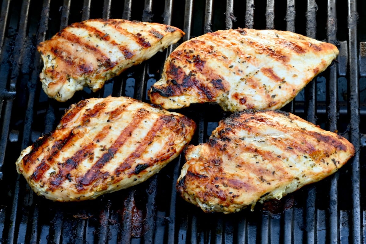 6 Side view of four grilled chicken breasts on a grill with defined grill marks