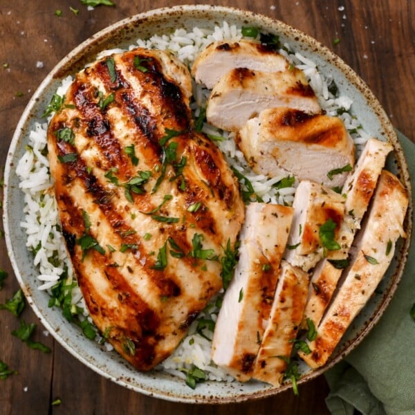 top view of grilled chicken breast in a bowl of rice with cilantro on top