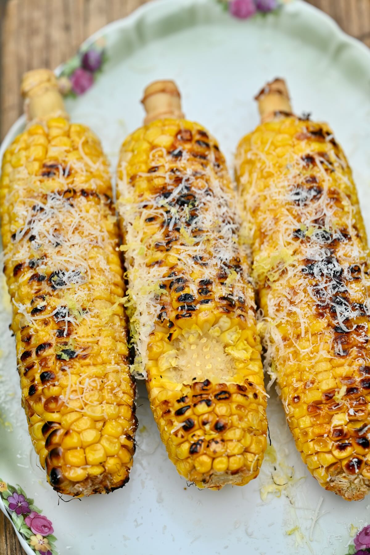 side view of three grilled corn on the cop with grated parmesan and lemon zest!
