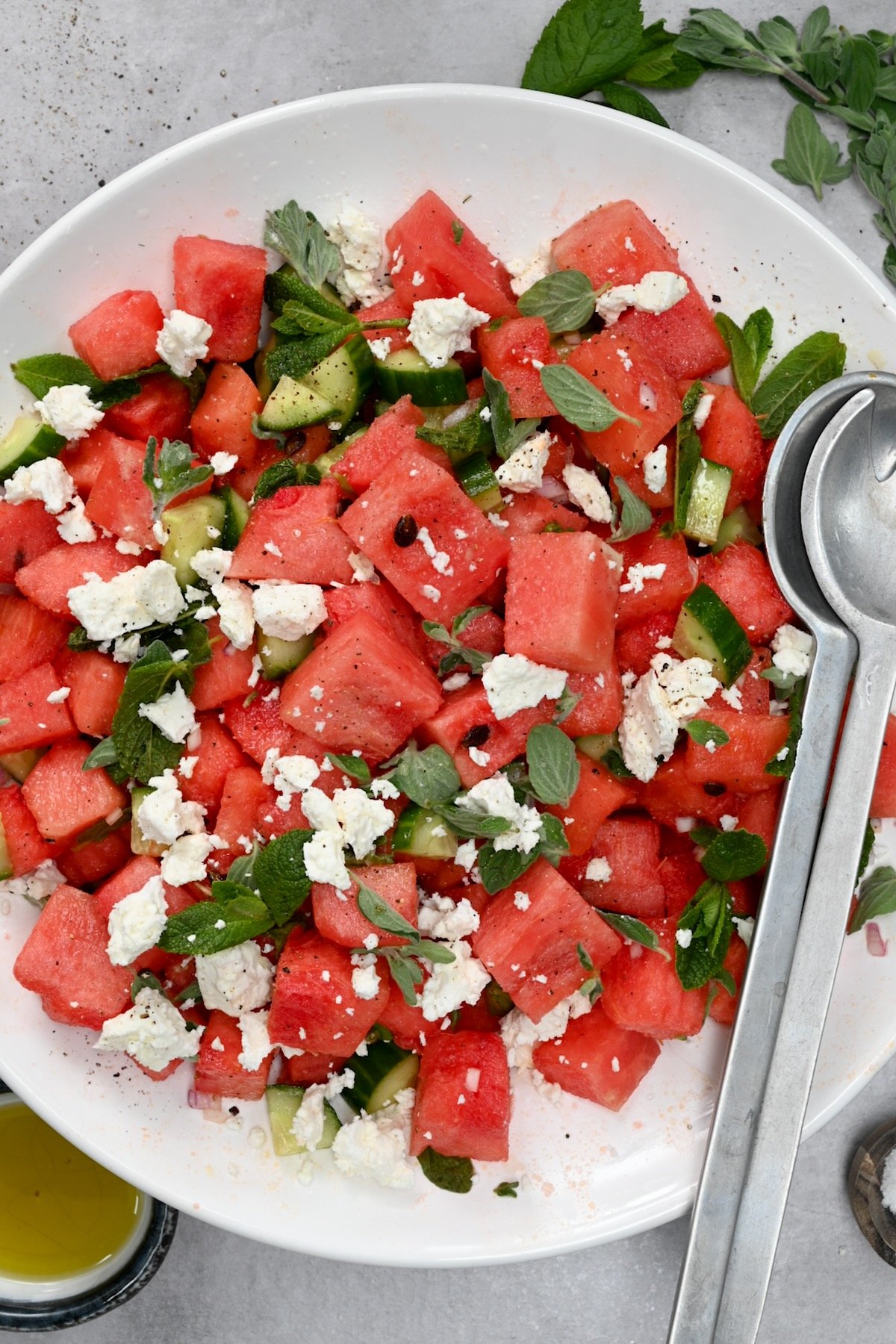 Top view of watermelon feta salad with herbs on a gray background.