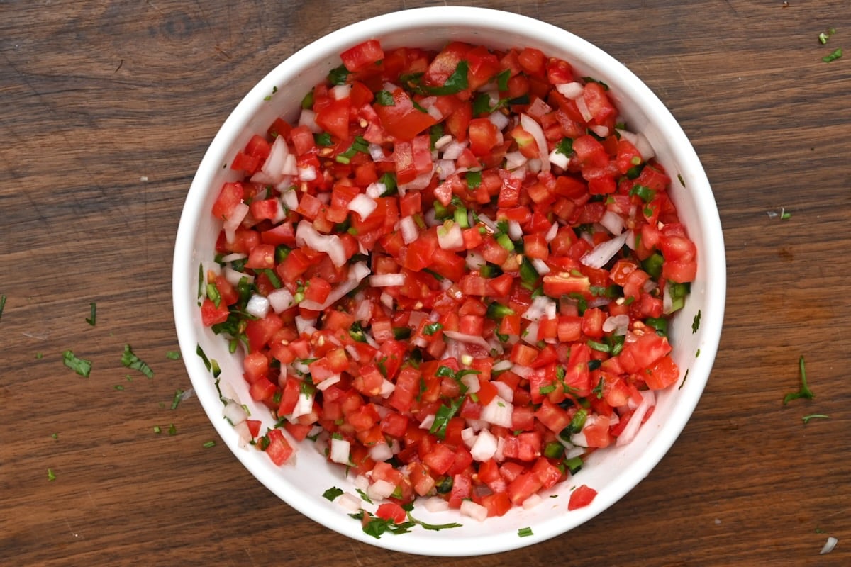 Finished pico de gallo in a white bowl on a wooden background. - 15