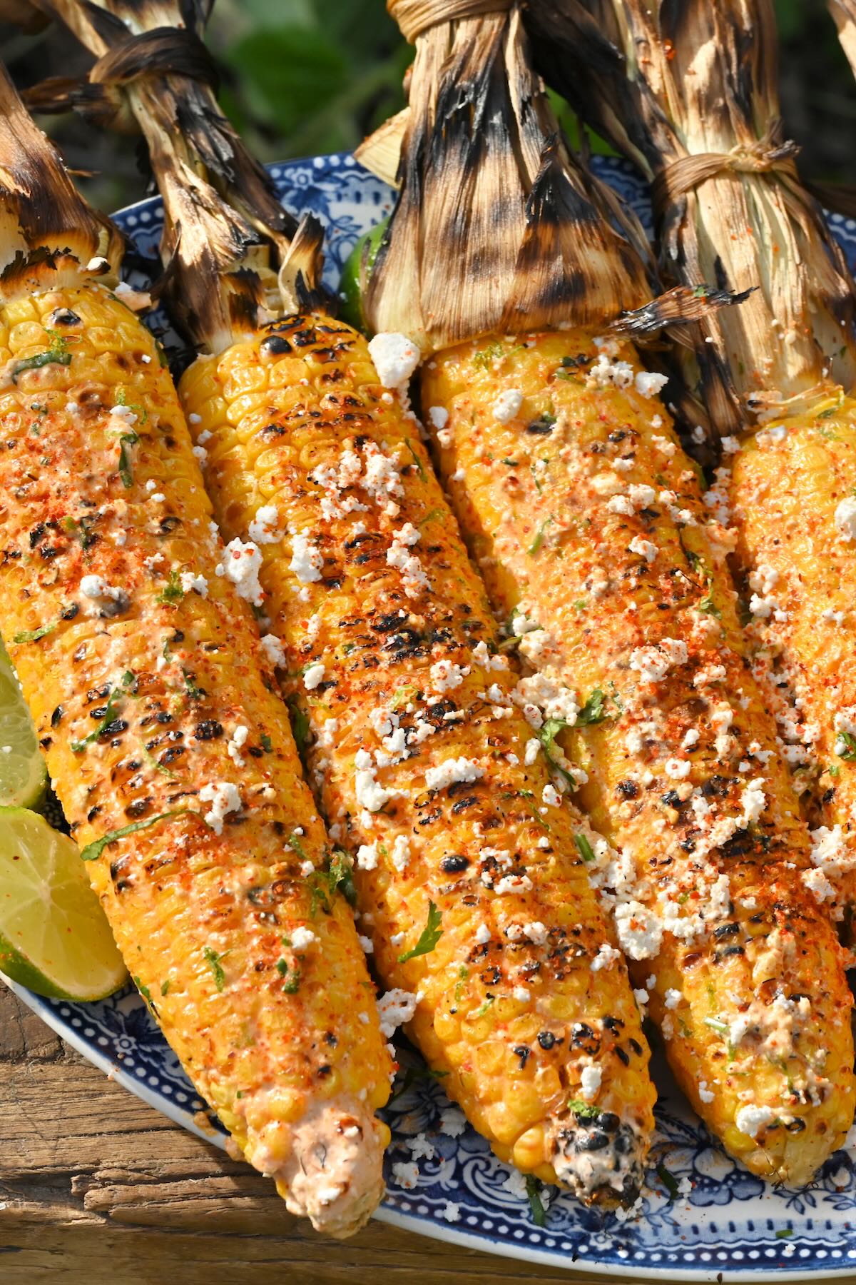 side view of four mexican street corn elotes in a blue plate.