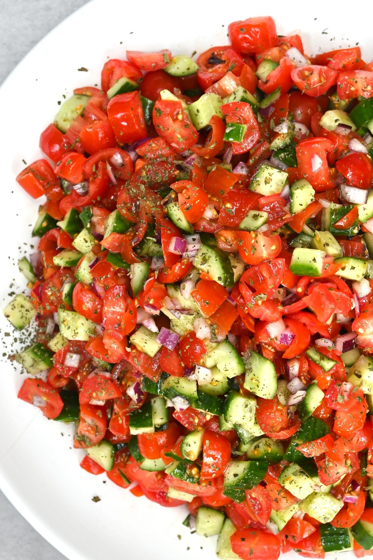 Top view close-up of Shirazi salad with tomatoes, onions, cucumber, and dried mint in a white plate on a gray background. - 6