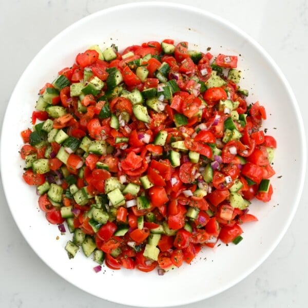 top view of shirazi salad in a white large plate on white marble background.