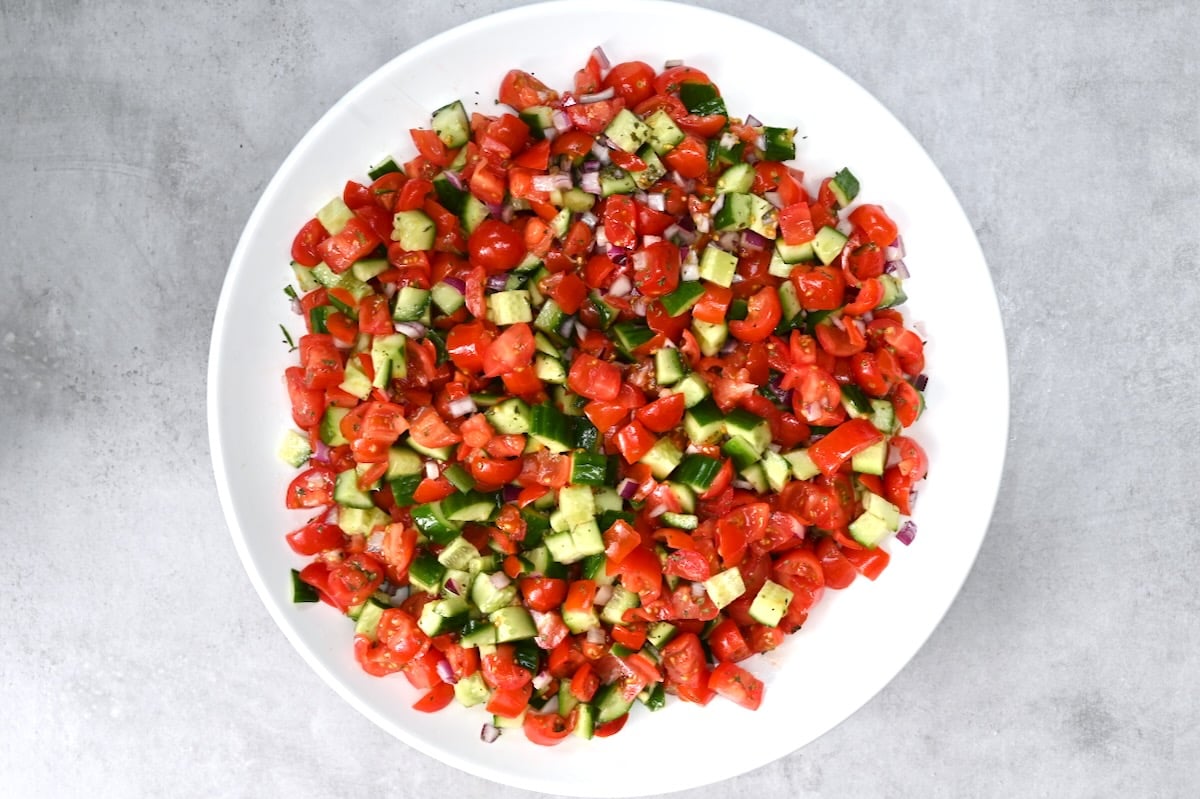 Shirazi salad made with chopped cucumber, tomato, and onion, fully mixed in a white bowl on a grey surface. - 9