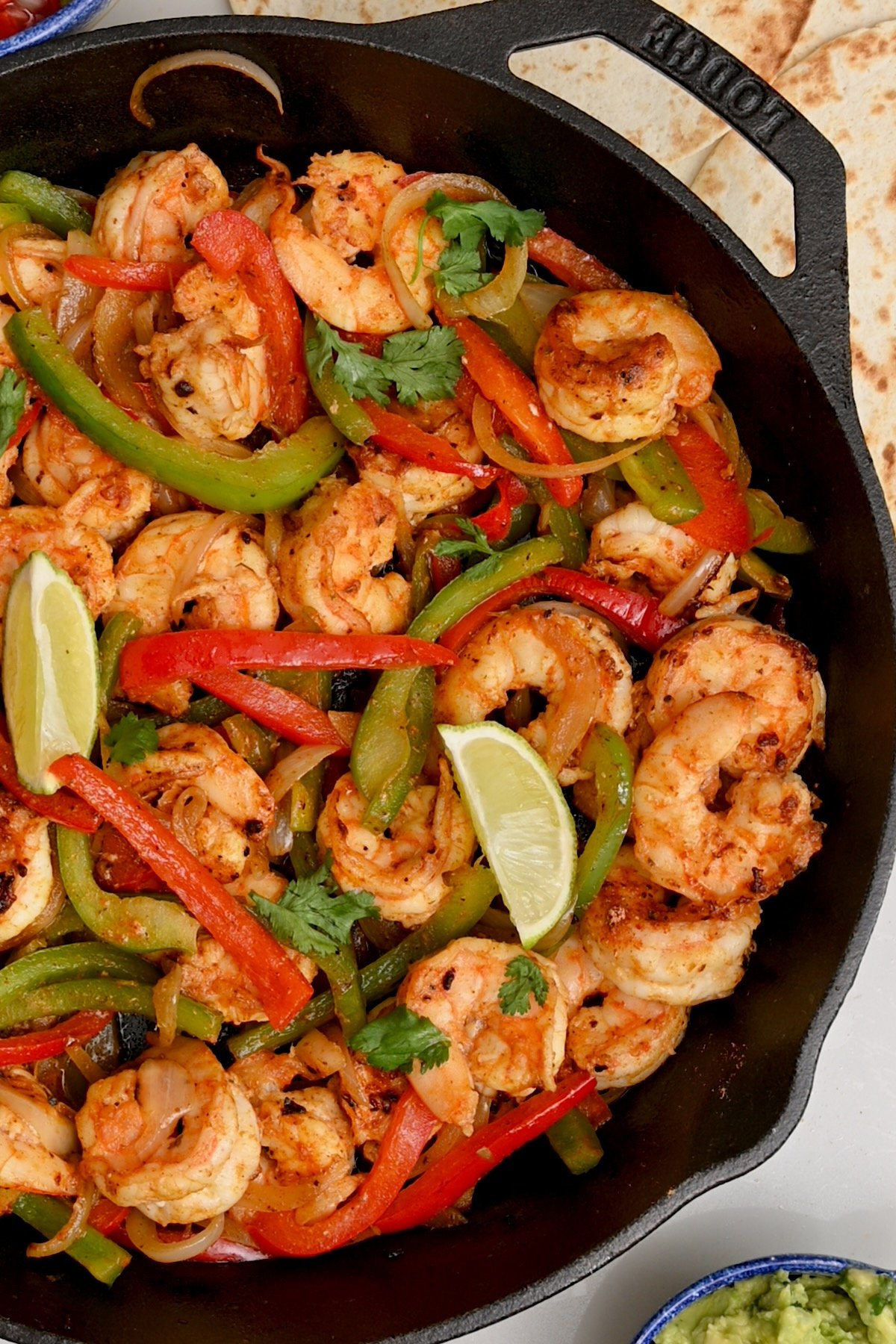 Top view close-up of shrimp fajitas in a black cast iron skillet.