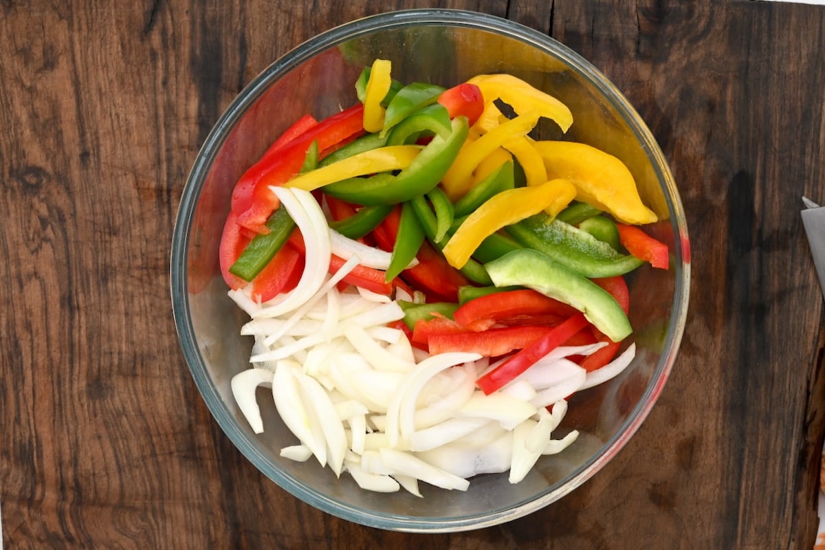 sliced peppers and onions in a glass bowl