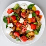 Top view of panzanella salad served in a large white plate on a white marble background. - 13