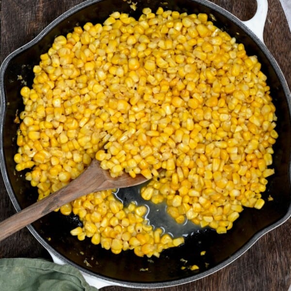 Top view of Southern fried corn cooking in a black skillet.