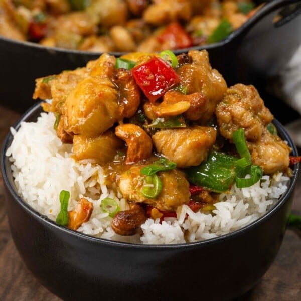 Cashew chicken served over steamed rice in a small black bowl.