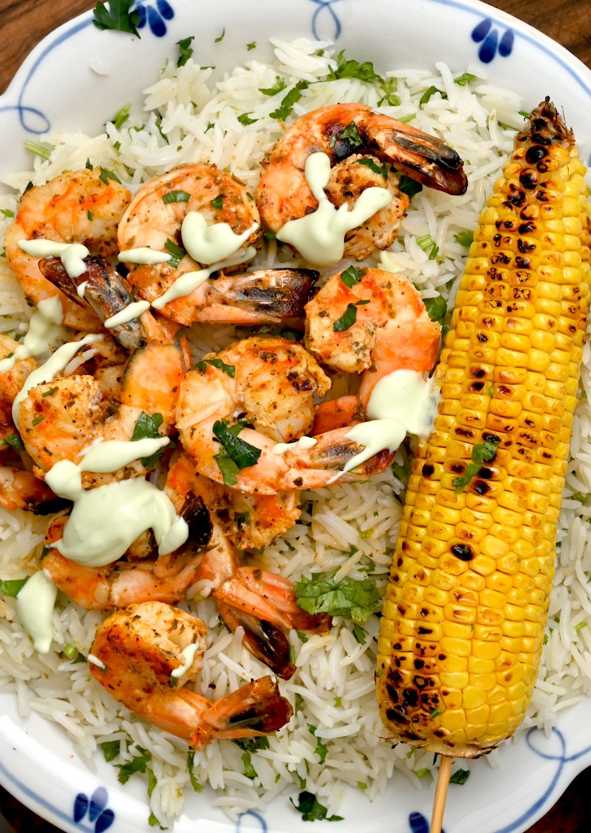 Grilled shrimp without skewers – Side view of grilled shrimp served over cilantro lime rice with sauce and grilled corn.