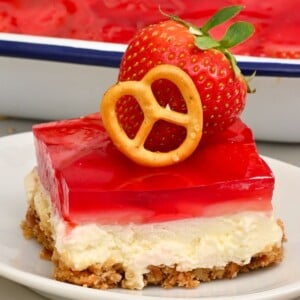 Slice of Strawberry Pretzel Salad with all three layers, topped with a small pretzel and a fresh strawberry.