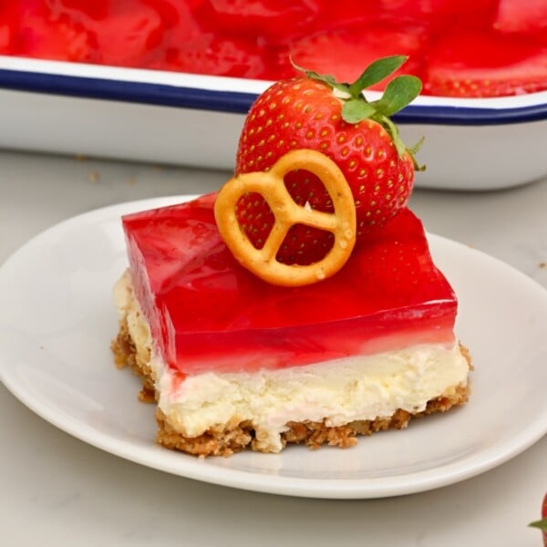 Slice of Strawberry Pretzel Salad with all three layers, topped with a small pretzel and a fresh strawberry.