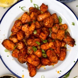 top view of air fryer salmon bites in a white plate with blue rim
