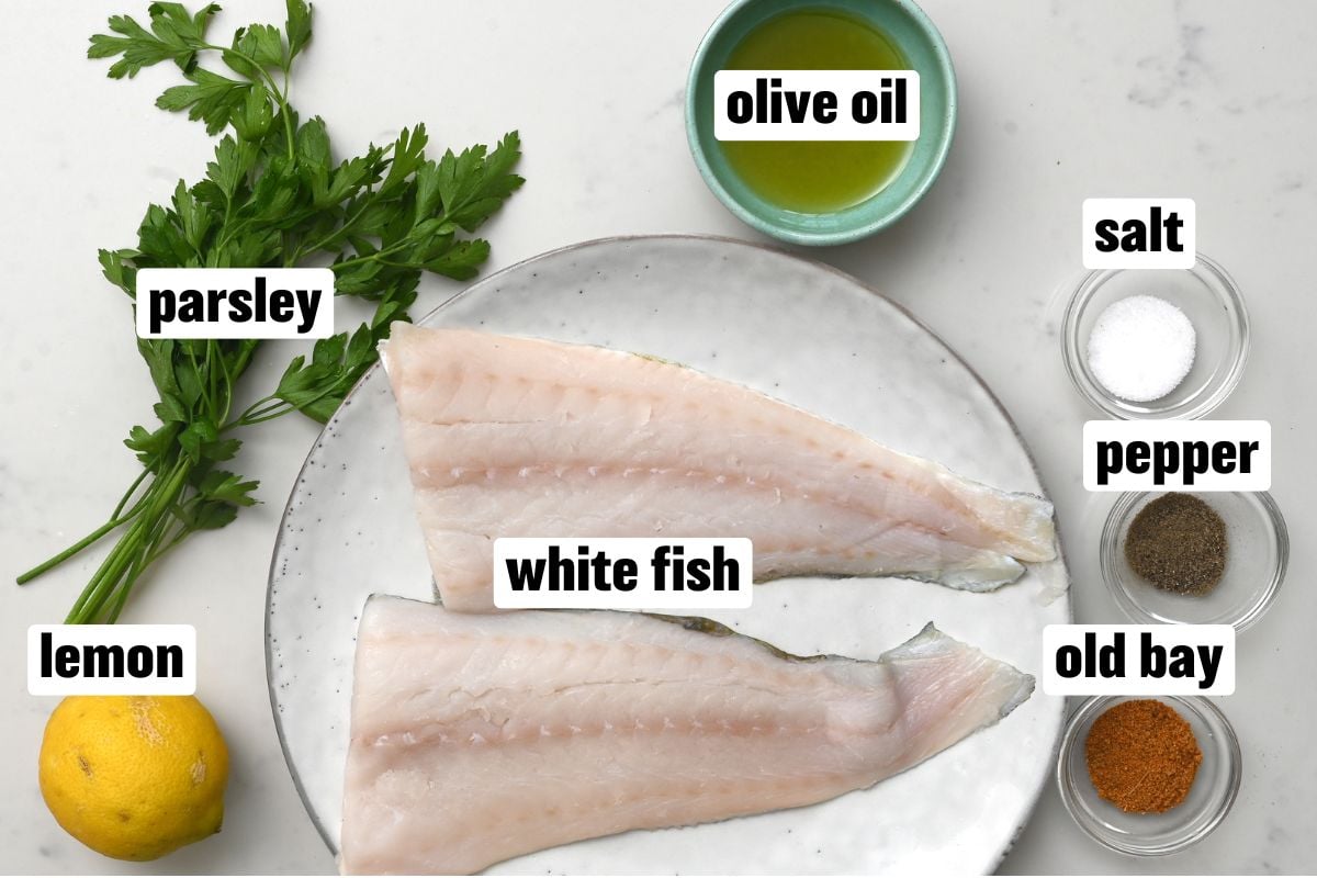 Top view of the ingredients for grilled fish on white marble.
