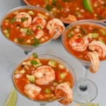 side view of three mexican shrimp cocktail glasses with large bowl in the background and lime wedges - 7
