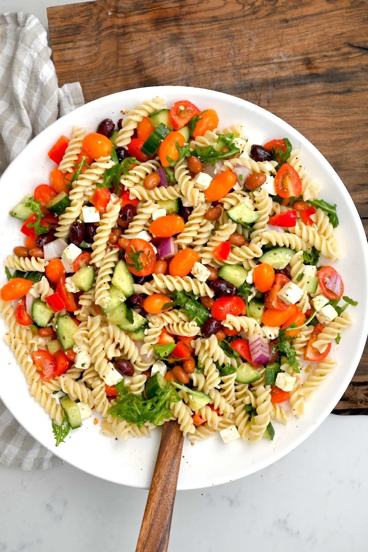 top view of pasta salad in a white bowl on top of wooden chopping board - 1