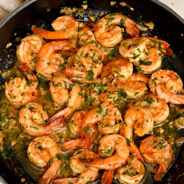 side view of of shrimp scampi in a black pan held by hand