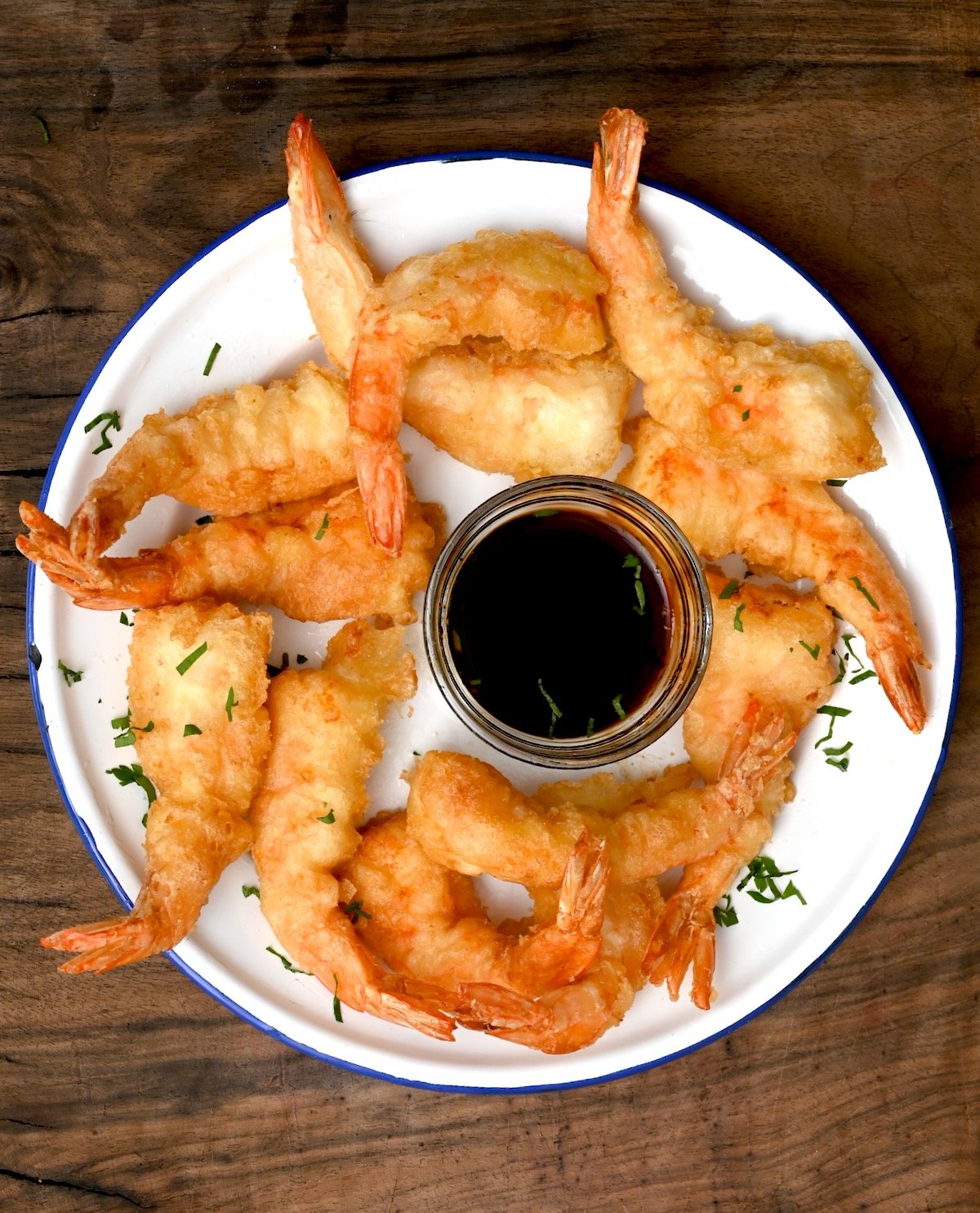 These crispy shrimp tempura are quick to make and perfect for a tasty appetizer! Top view of crispy shrimp tempura on a white plate with blue rim and dipping sauce, perfect appetizer or snack