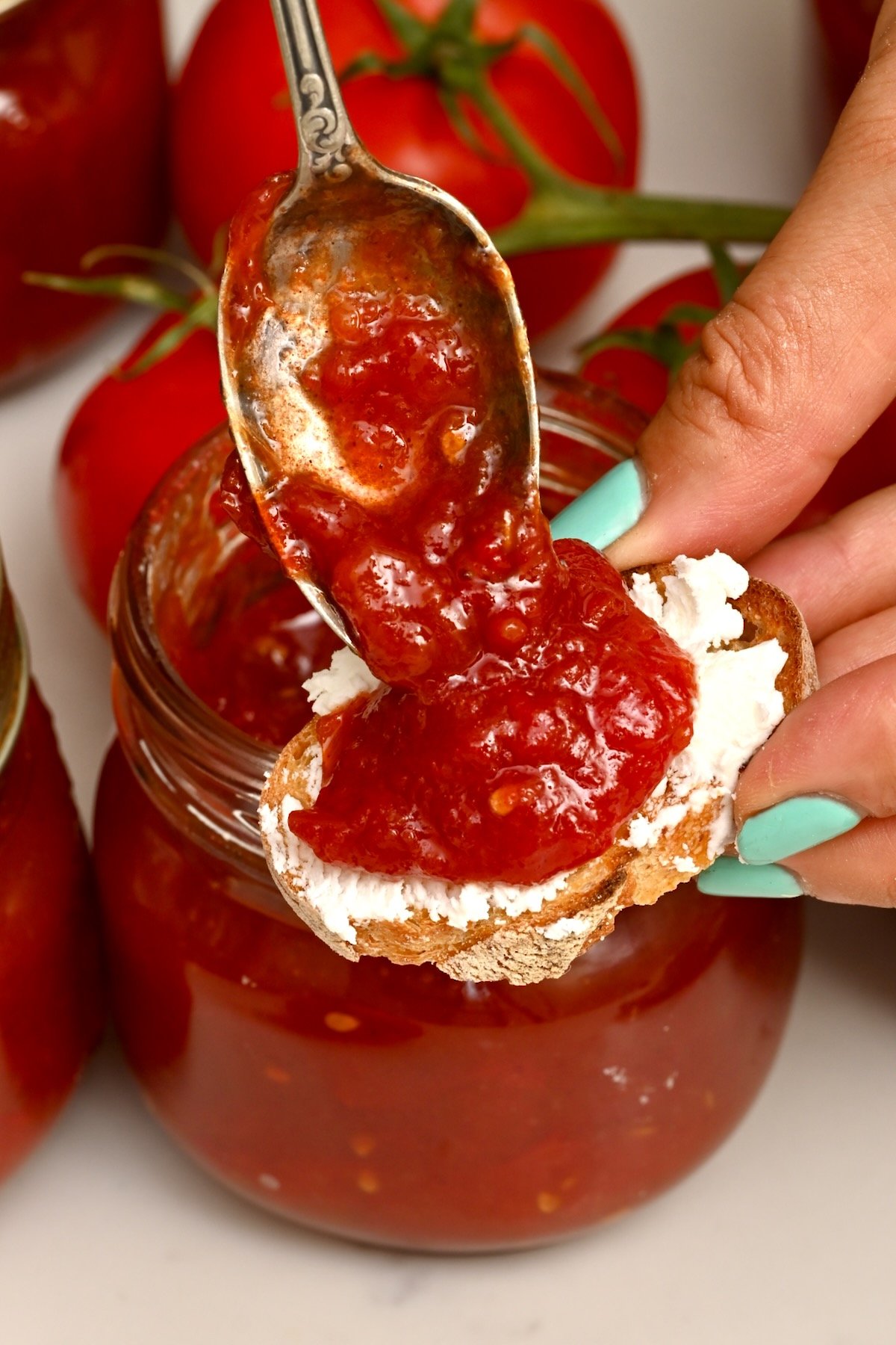 side view photo of tomato jam being drizzled on toast with goat cheese on it - 2