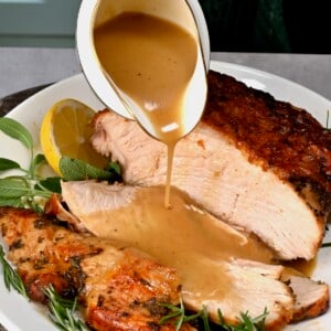 square photo of Turkey gravy being poured on sliced turkey breast