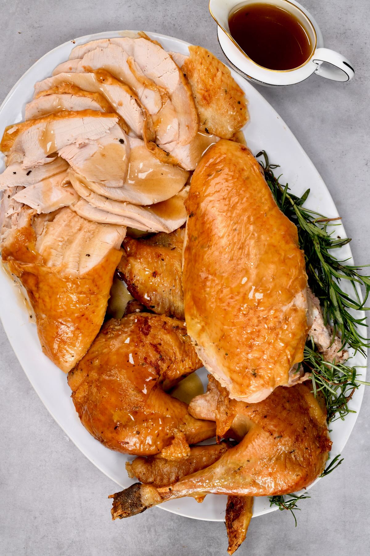 top view of carved turkey in a large white plate with gravy on top and grazy jug on the side - 2