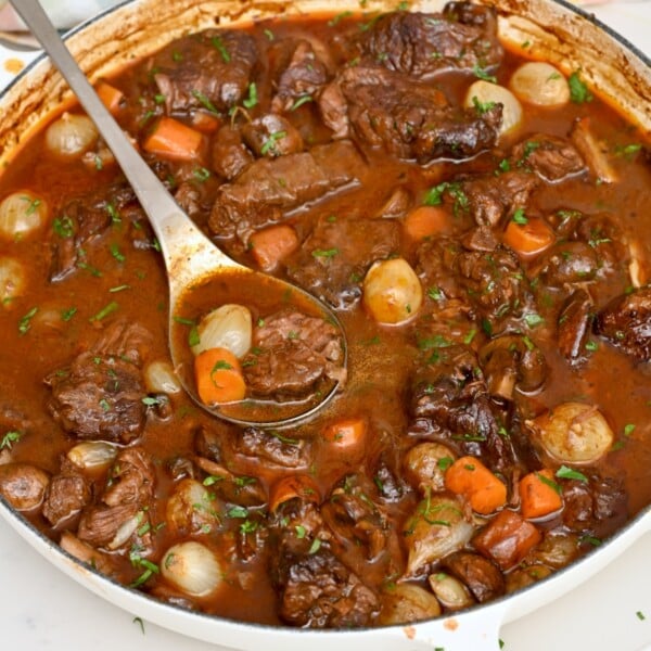 adle lifting tender beef, carrots, mushrooms, and pearl onions from a rich beef bourguignon sauce.