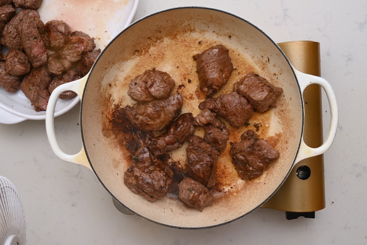 Marinated beef pieces sizzling in a hot pot as they brown for beef bourguignon. - 12