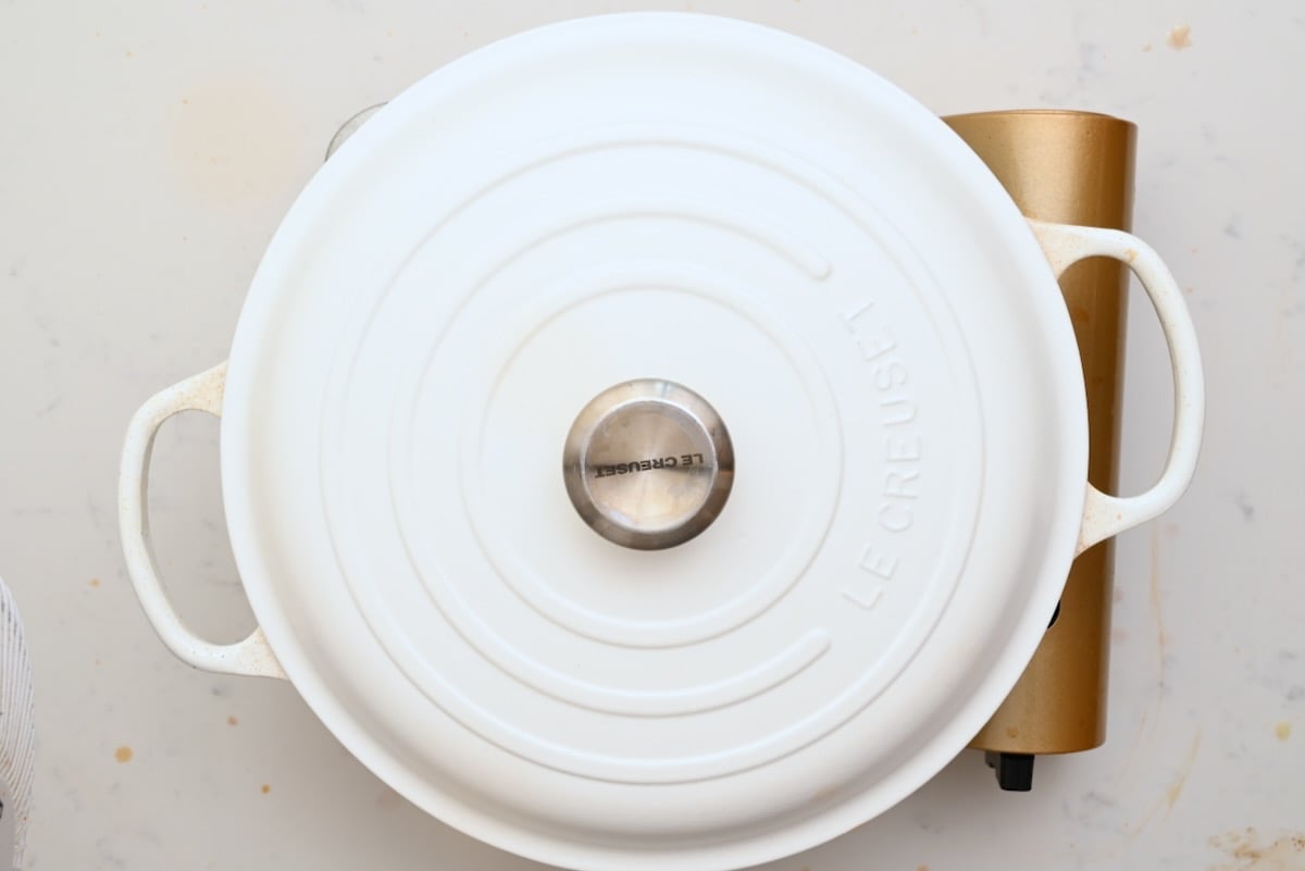 A Dutch oven covered with its lid while beef bourguignon cooks slowly inside. - 23