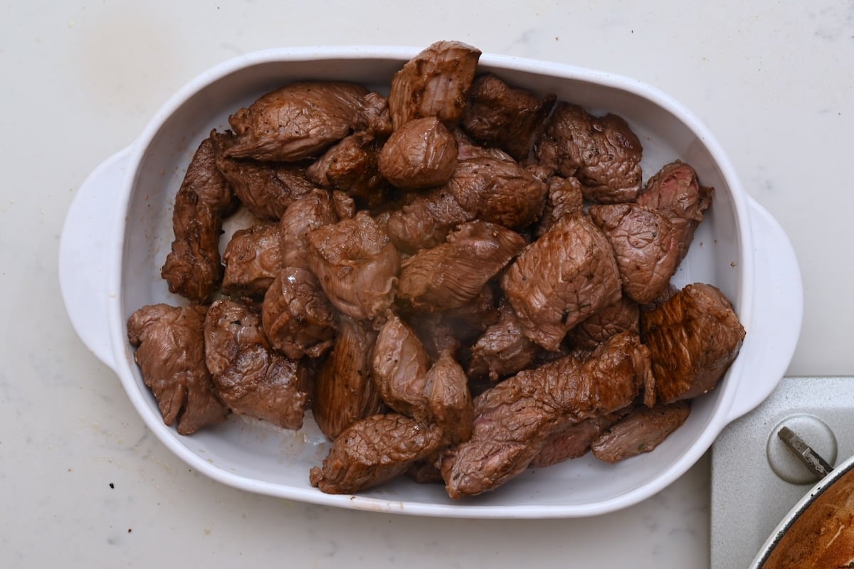 Seared beef pieces resting in a dish after browning, ready to continue cooking for beef bourguignon. - 13