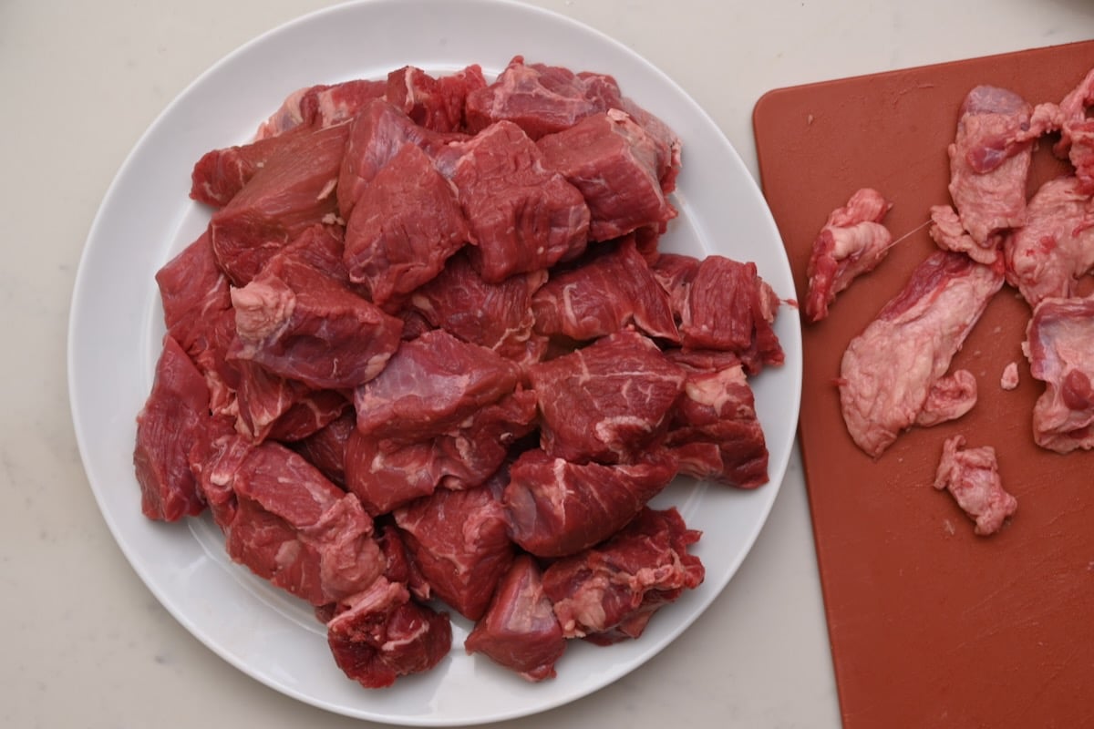 Trimmed chunks of beef on a plate, prepped for making beef bourguignon. - 5