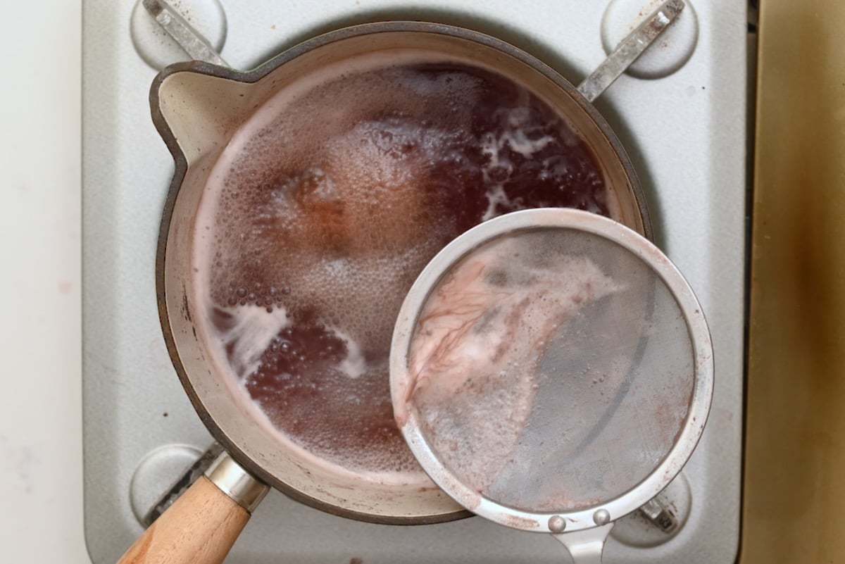 Skimming impurities from the boiling red wine marinade before using it in beef bourguignon. - 15