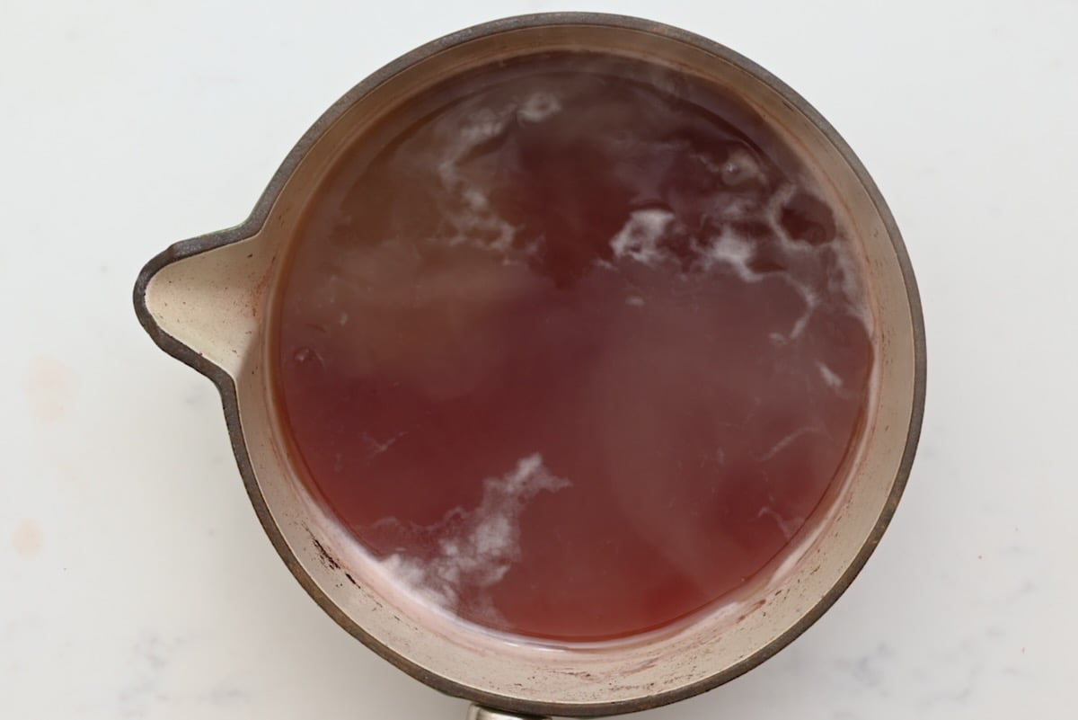 The red wine marinade boiling in a saucepan to remove alcohol before adding to beef bourguignon. - 17