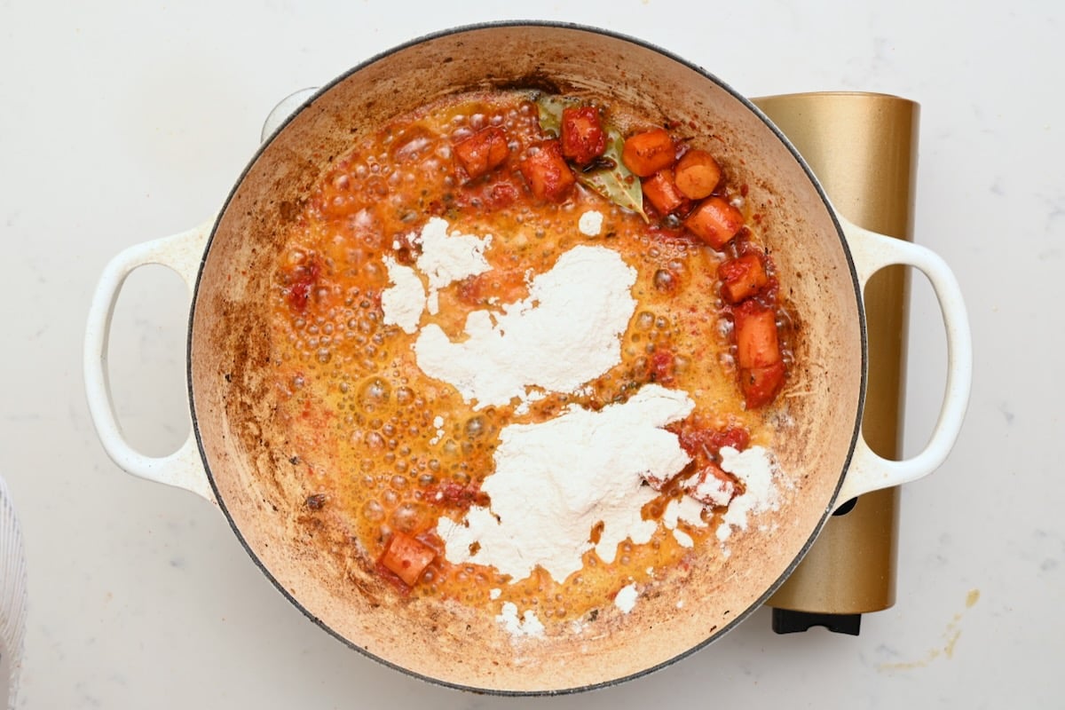 Flour sprinkled over sautéed carrots and aromatics to form a thickening base for beef bourguignon. - 21