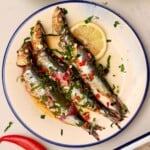 Three roasted sardines served on a plate with lemon slice. - 15