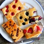 Sliced sheet pan pancakes with berries, chocolate chips, and drizzled with maple syrup. - 9