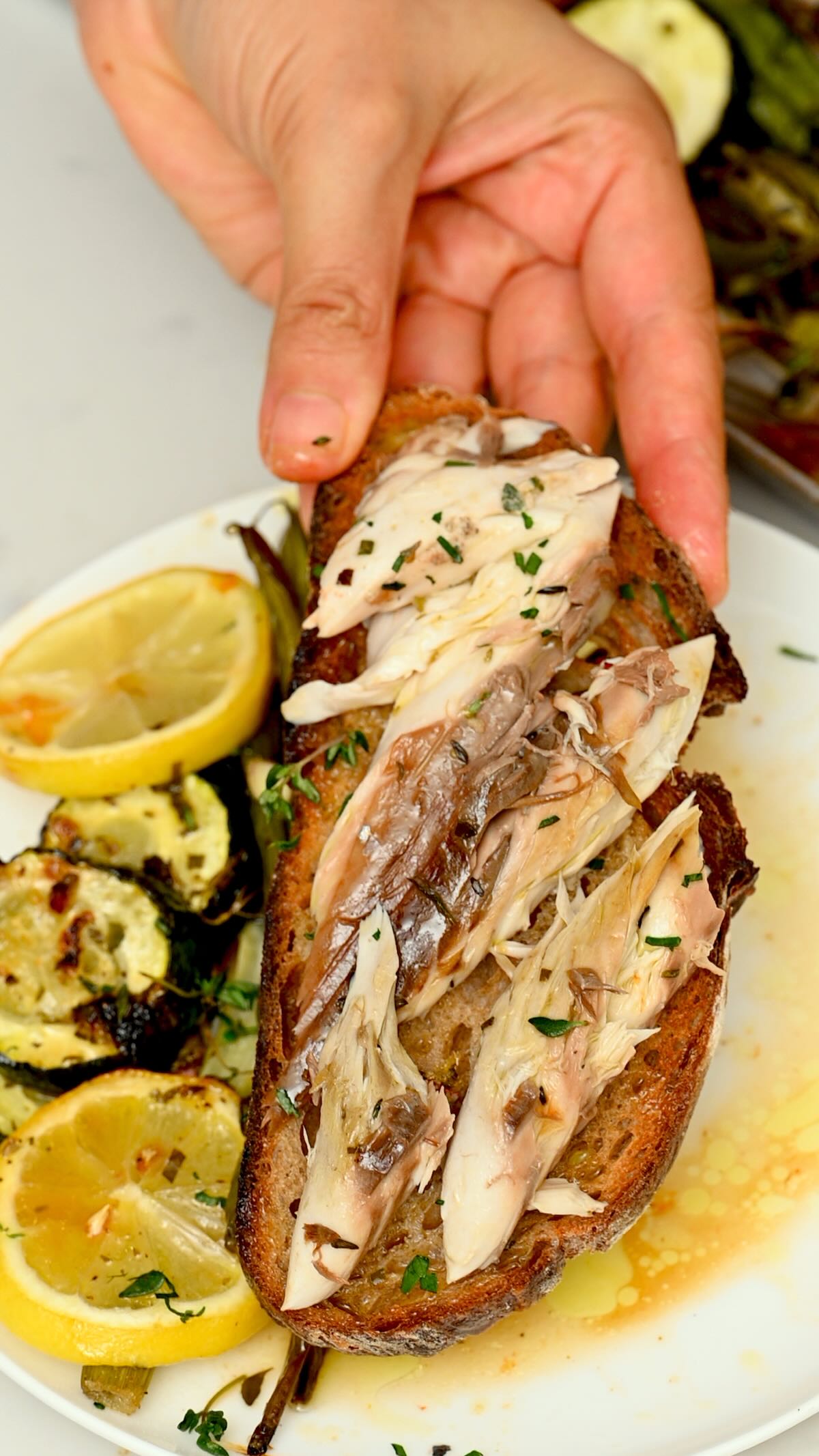 Flaked oven-baked mackerel served on toasted bread with lemon, herbs, and roasted vegetables on the side. - 5